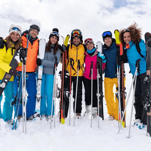 Grup d’amics somrient a la neu amb els esquís i els bastons